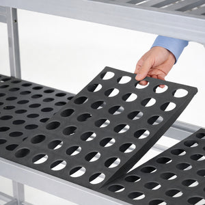 Person holding a black perforated mat over a metal shelf